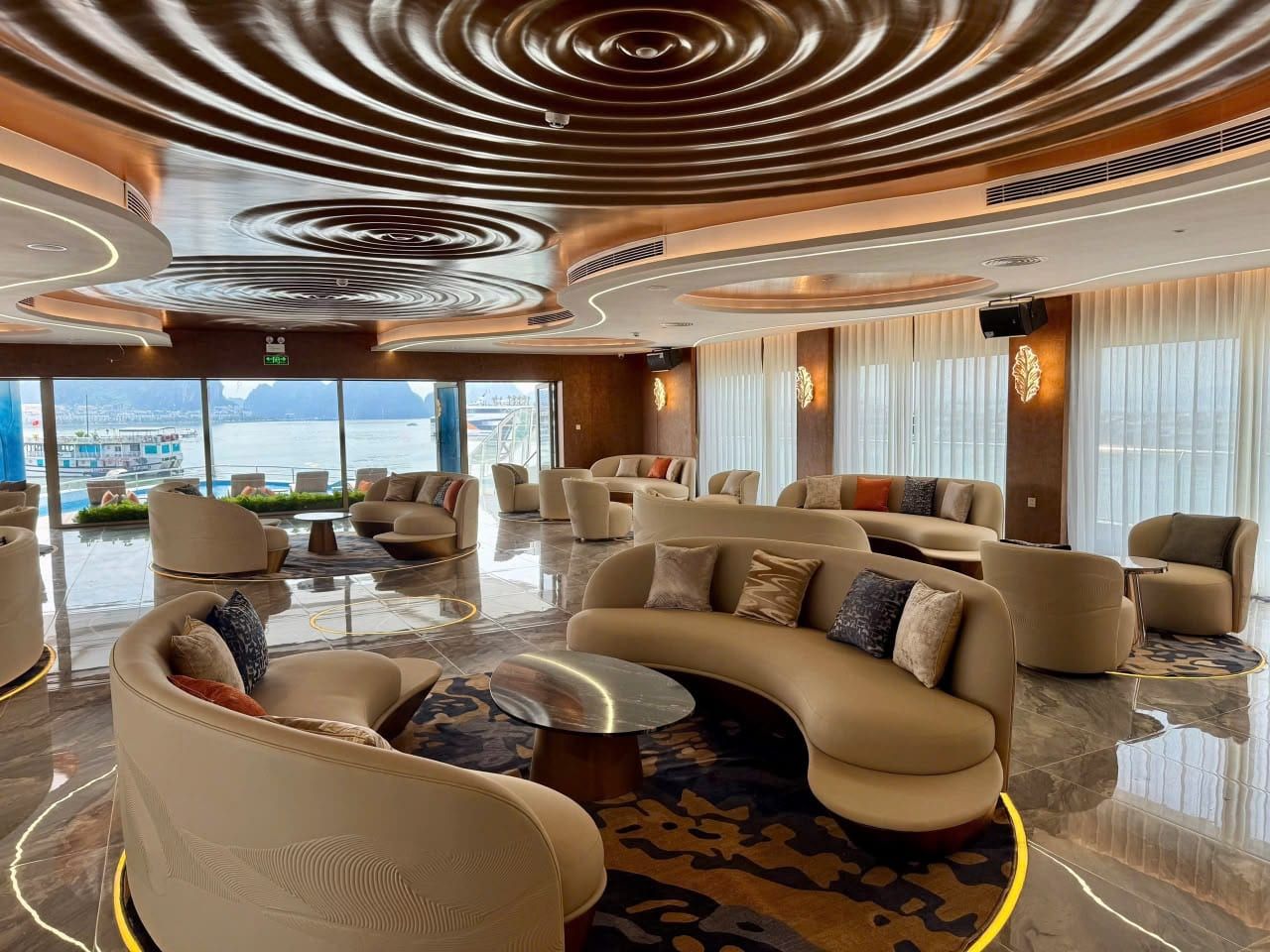 The Athena Premium lounge, curved banquettes beneath a slatted ceiling and bay windows