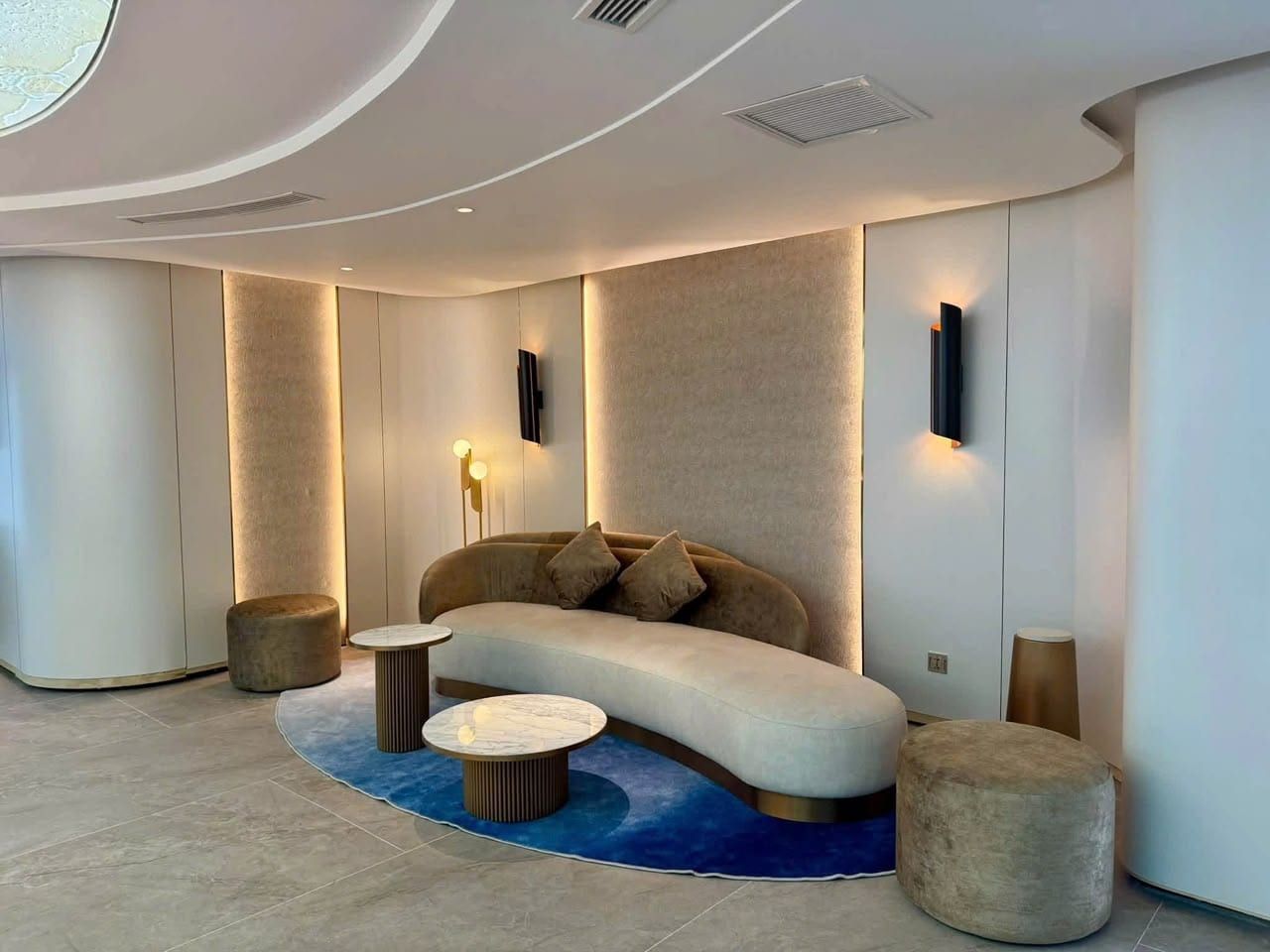 A suite living area on Athena Premium with a curved sofa and circular rug