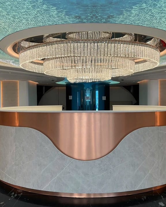 The reception lobby aboard Athena Premium beneath a tiered chandelier