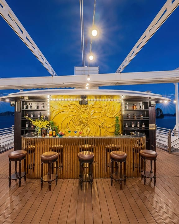 The Athena Royal deck bar at dusk beneath festoon lights
