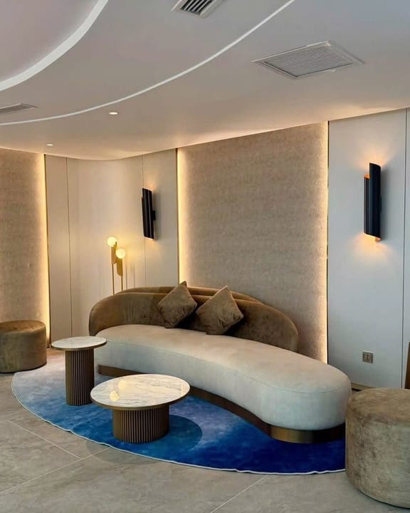 The living area of an Athena Premium suite, curved sofa and blue rug