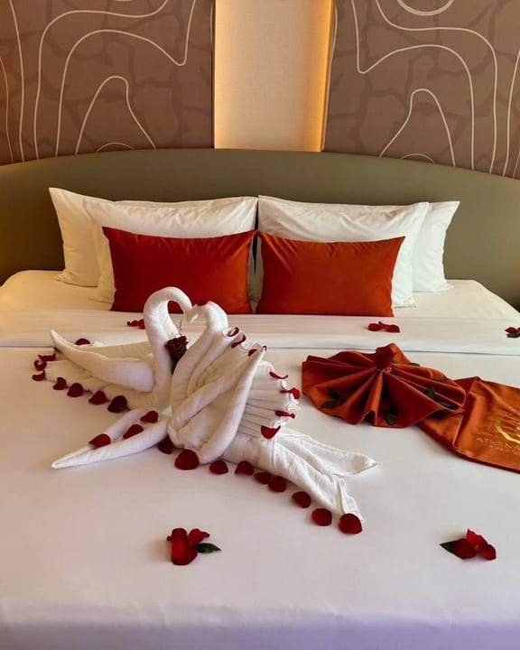 An Athena Premium bed turned down with towel swans and rose petals