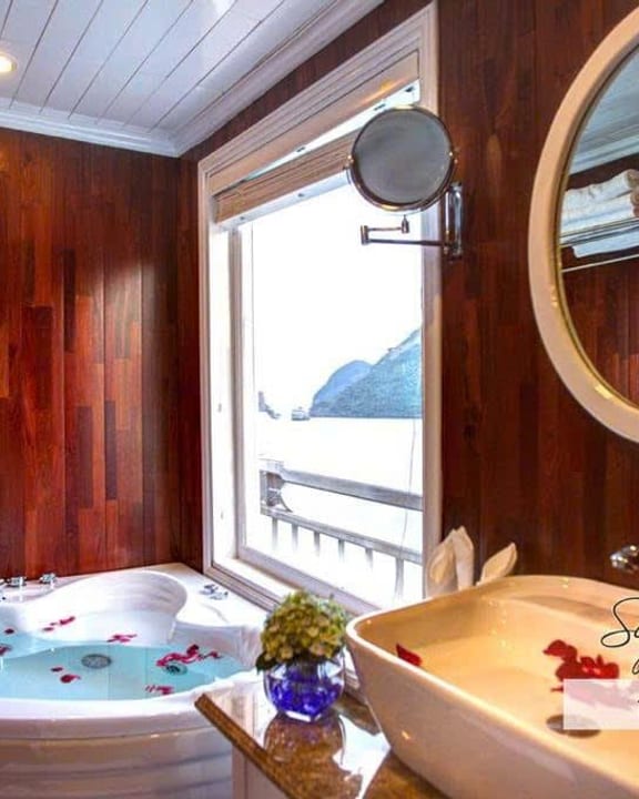 A corner bath beside a round window in the Elite Family Suite